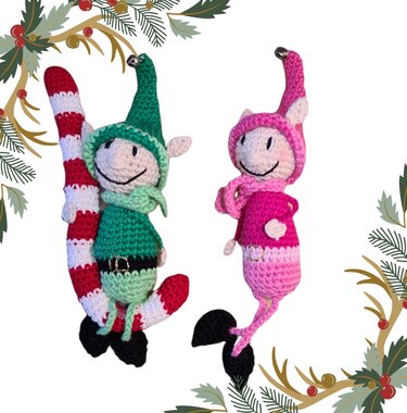 Zwei gehäkelte Amigurumi-Elfen, eine grüne mit rot-weißer Zuckerstange und eine pinke, vor weißem Hintergrund mit Tannenzweigen am Rand.