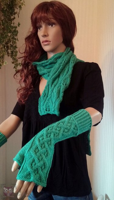 Mannequin mit grünem Zopfmuster-Schal und langen, fingerlosen Armstulpen mit Rippenbund