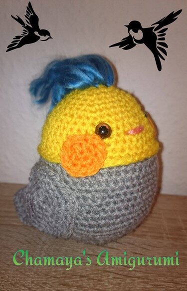 Gehäkeltes Amigurumi-Vögelchen mit gelbem Kopf, orangefarbener Wange und grauem Körper