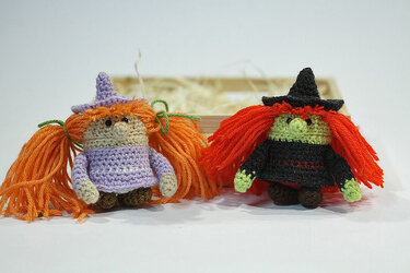 Zwei gehäkelte Hexen-Amigurumi mit Spitzhüten und bunten Garnhaaren vor hellem Hintergrund