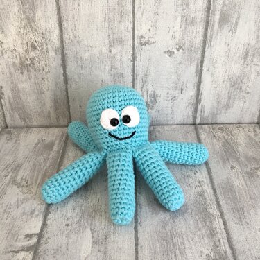 Hellblauer gehäkelter Oktopus-Amigurumi mit großen Augen und lächelndem Mund