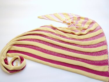 Gestricktes Dreieckstuch mit pinken und gelben Streifen auf weißem Hintergrund