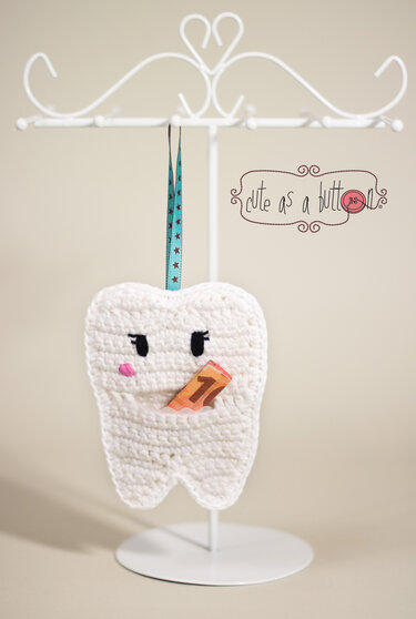 Gehäkelte weiße Zahntasche mit aufgesticktem Gesicht an blauem Band