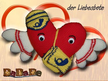 Rotes gehäkeltes Amigurumi-Herz mit Flügeln, Postmütze und kleiner Tasche vor einem Hintergrund mit Herzmotiven.