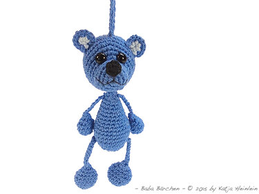 Handgehäkelter blauer Teddybär mit schwarzen Augen an einer Schlaufe hängend