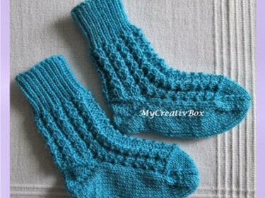 Zwei türkisfarbene gestrickte Kindersocken mit vertikalem Muster und Rippbündchen