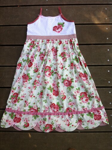 Weißes Kinderkleid mit roten und rosa Rosen, gepunktetem Oberteil, gestreifter Taillenborte, Spaghettiträgern und Muschelsaum