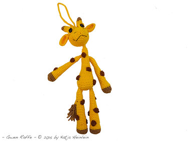 Gelbe gehäkelte Amigurumi-Giraffe mit braunen Punkten und Aufhängeschlaufe vor weißem Hintergrund.