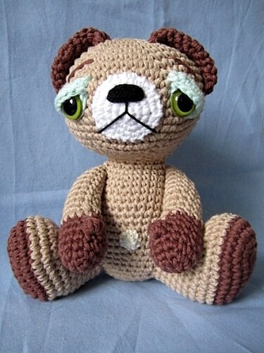 Sitzender gehäkelter Amigurumi-Teddybär in Beige und Braun mit grünen Augen