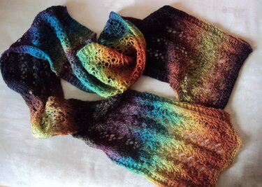 Gestrickter Schal mit Regenbogen-Farbverlauf und offenem Lochmuster auf hellem Untergrund