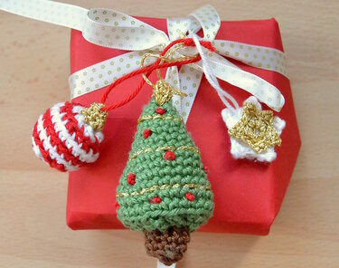 Gehäkelte Weihnachtsanhänger: grüner Tannenbaum, rot-weiße Kugel und weißer Stern auf roter Geschenkbox