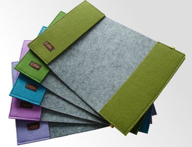 Fächerförmig angeordnete graue Filztaschen mit farbigen Seiten in Grün, Türkis, Violett und Lila.