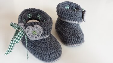 Pair of dark gray crocheted baby booties with green-and-white gingham ribbon on a white background.