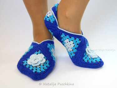 Blaue gehäkelte Ballerinas aus Granny‑Squares mit weißen Blütenapplikationen und kontrastreicher Umrandung