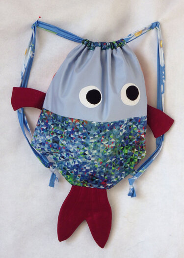 Fischförmiger Kordelzugbeutel in Hellblau mit buntem geometrischem Muster und roten Flossen