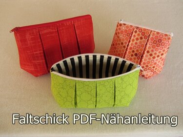 Drei gefaltete Kosmetiktaschen in Grün, Rot und Orange mit Reißverschluss, grüne Tasche mit gestreiftem Innenfutter sichtbar