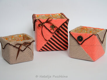 Drei gestrickte quadratische Aufbewahrungskörbe in Beige und Koralle mit Paisley-Futter, Knopf- und Bandverzierung