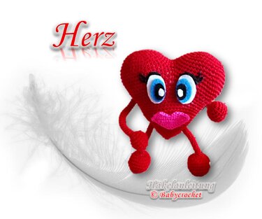 Rotes gehäkeltes Herz-Amigurumi mit Gesicht auf weißer Feder