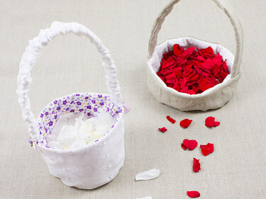 Zwei runde gefütterte Utensilos mit Henkel, eines mit gerafftem Griff, eines mit glattem Griff, gefüllt mit Rosenblättern