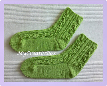 Leuchtend grüne handgestrickte Socken mit Zopfmuster