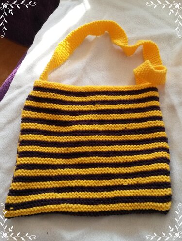 Gestrickte gestreifte Tasche in Gelb und Dunkelbraun mit gelbem Schultergurt auf weißer Decke