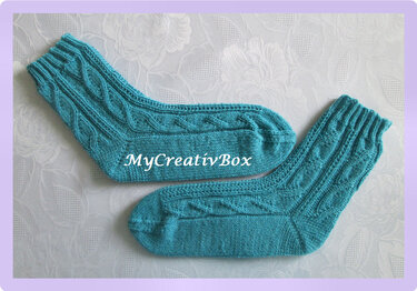 türkise gestrickte Socken mit Zopfmuster auf hellem Untergrund