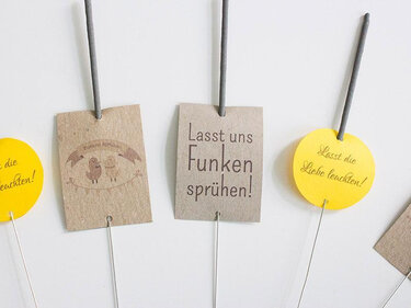 Wunderkerzen mit braunen Kraftpapier- und gelben Kartonanhängern mit kurzen Sprüchen