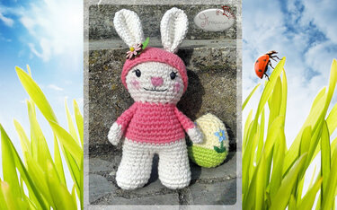 Gehäkelter weißer Hase mit rosa Kapuze und gehäkeltem Osterei