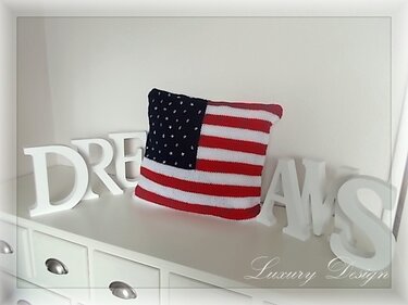 Quadratisches gestricktes Kissen mit US-Flaggenmuster auf weißer Kommode