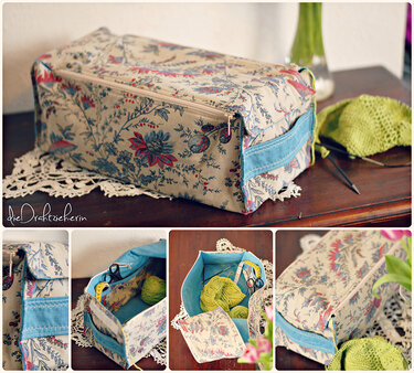 Rechteckige Stofftasche mit Blumenmuster, Reißverschluss und blauem Seitengriff, teils mit Strickgarn zu sehen.