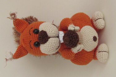 Orangefarbenes gehäkeltes Eichhörnchen-Amigurumi mit beigen Akzenten und brauner Eichel
