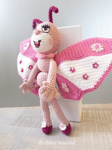 Gehäkelter rosa-weißer Amigurumi-Schmetterling mit Blumen auf den Flügeln