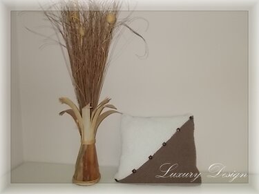 Gestrickter Kissenbezug in Weiß und Braun mit diagonaler Knopfleiste neben Vase mit Trockenblumen