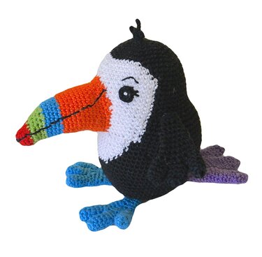 Nahaufnahme eines gehäkelten Amigurumi-Tukans mit mehrfarbigem Schnabel und blauen Füßen