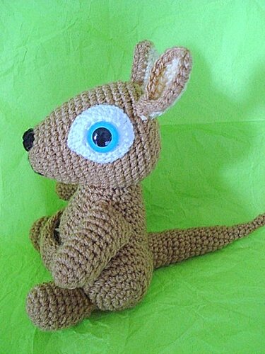 Gehäkeltes braunes Amigurumi-Känguru mit weiß-blauem Auge, seitliche Ansicht