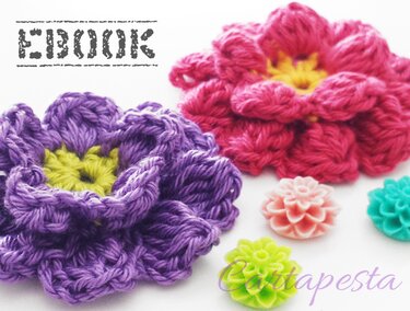 Mehrlagige Häkelblüten in Lila und Pink mit kleinen dekorativen Blumensteinen