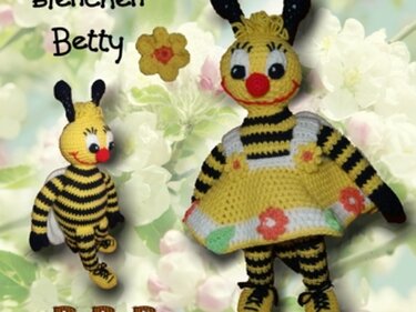 Zwei gehäkelte Bienen, eine größere mit Blumenkleid und eine kleinere gestreifte Biene vor hellem Blumenhintergrund.