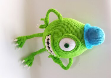 Gehäkeltes grünes Einauge-Monster mit blauem Detail und spitzen Zähnen