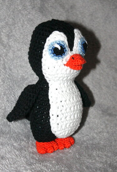 Gehäkelter schwarzer und weißer Pinguin-Amigurumi mit orangefarbenem Schnabel und Füßen