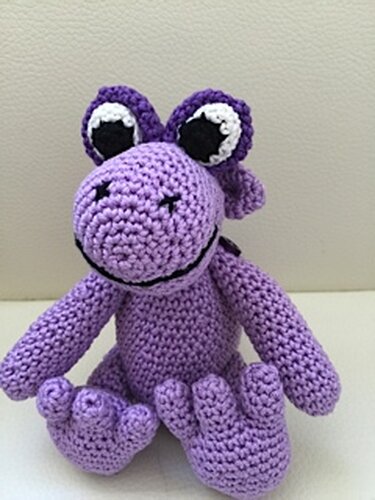 Vollständig gehäkeltes lila Drachen-Amigurumi sitzend mit markanten Augen