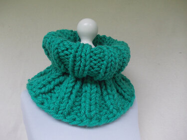 Grüner, dick gestrickter Loop-Schal mit Rippenmuster auf weißer Büste