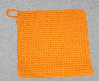 Quadratischer orangefarbener gehäkelter Topflappen mit Schlaufe
