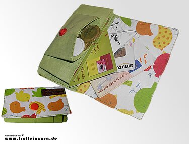 Grüne Stoff-Geldbörse mit buntem Vogelmuster, geöffnetes Innenfach mit Münzen, Karten und Druckknopfverschluss