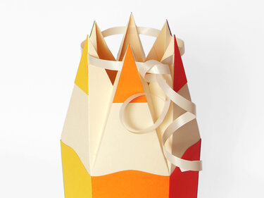 Papier-Geschenkbox in Buntstift-Optik mit spitzen Deckeln und cremefarbenem Band