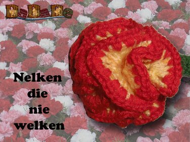 Gehäkelte rote Nelkenblüte mit gelbem Zentrum vor einem Hintergrund aus echten Nelken und dem Schriftzug ‚Nelken die nie welken‘.