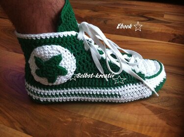 Gehäkelter grüner und weißer Hausschuh im Sneaker-Stil mit Schnürsenkeln und Sternapplikation
