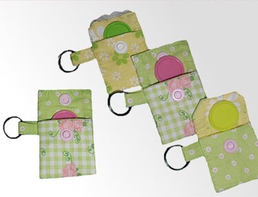 Vier kleine genähte Täschchen aus grün-gelbem Baumwollstoff mit rundem Kunststoffeinsatz und Schlüsselring