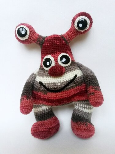 Gehäkeltes Amigurumi-Monster rot-grau mit zwei Fühlern und gesticktem Lächeln