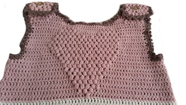 Gehäkelter rosa Babyschlafsack mit erhabenem Herzmuster, braunen Einfassungen, weißem Saum und Schulterknöpfen