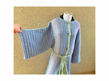 Gehäkelte Pastelljacke auf Mannequin mit weiten Ärmeln, Knopfleiste und geflochtenem Gürtel